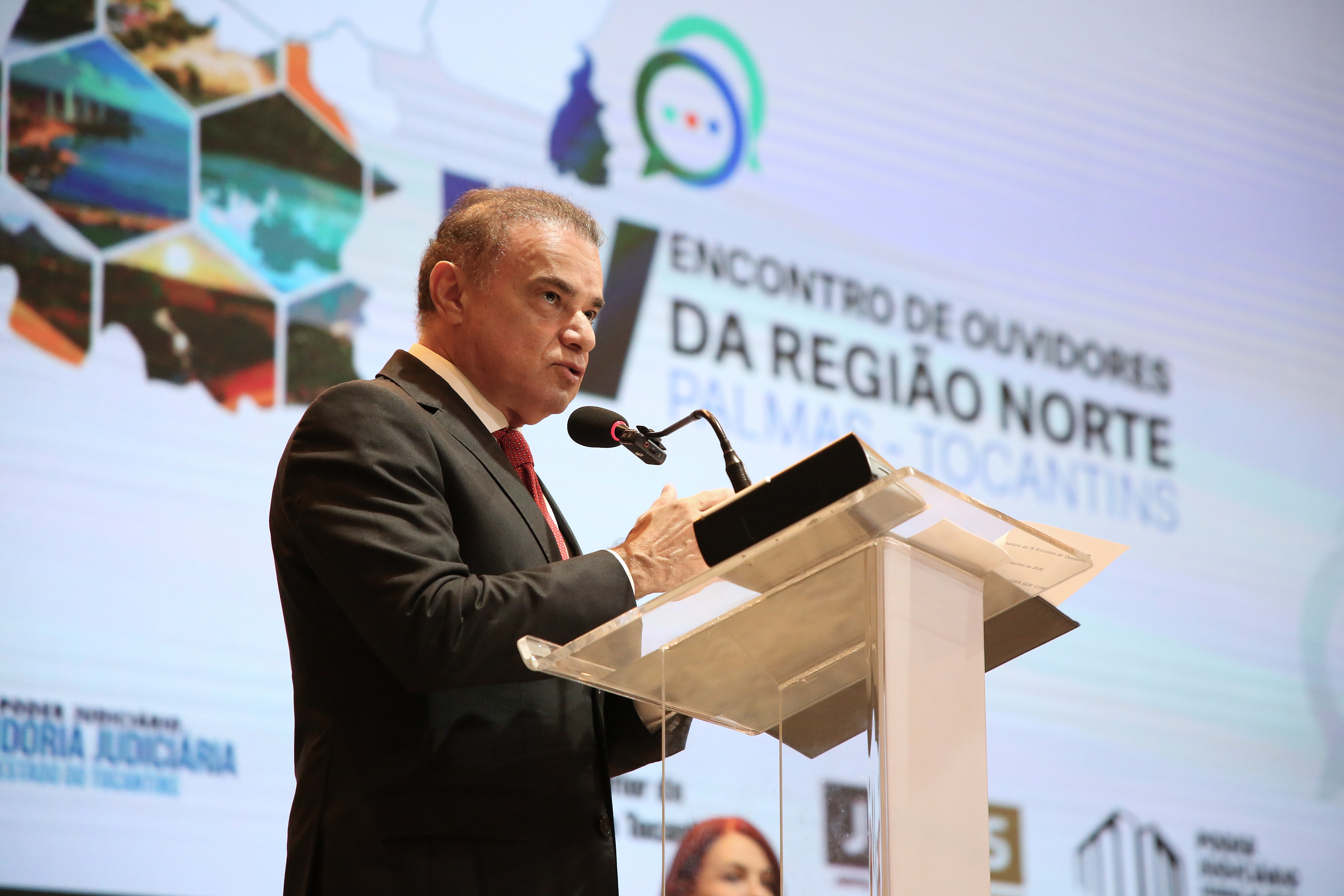O presidente do Colégio Nacional de Ouvidores Judiciais (Cojud), desembargador Abraham Peixoto Campos Filho, discursa no púlpito durante o IV Encontro de Ouvidores e Ouvidoras Judiciais da Região Norte. Ao fundo, o painel oficial do evento.