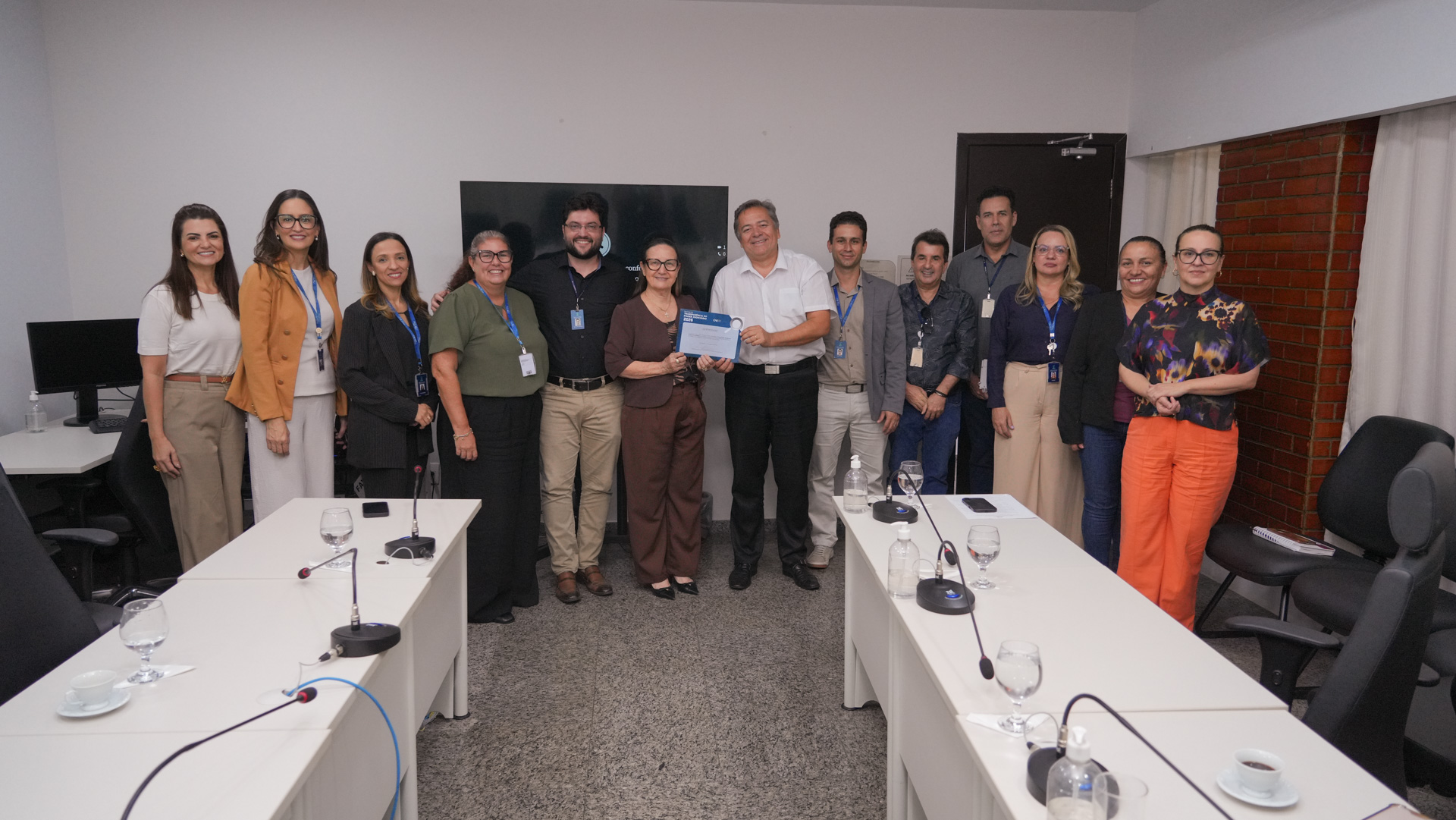 Grupo de homens e mulheres posa para foto em uma sala de reuniões. Ao centro, a presidente do TJTO, desembargadora Maysa Vendramini Rosal, e o juiz auxiliar da Presidência Arióstenis Guimarães Vieira seguram o certificado do Ranking da Transparência do Poder Judiciário 2026.