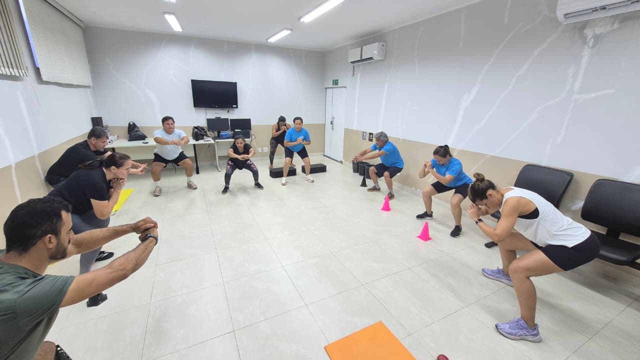 Participantes do projeto Judiciário na Medida fazem exercícios de agachamento durante atividade física em grupo.