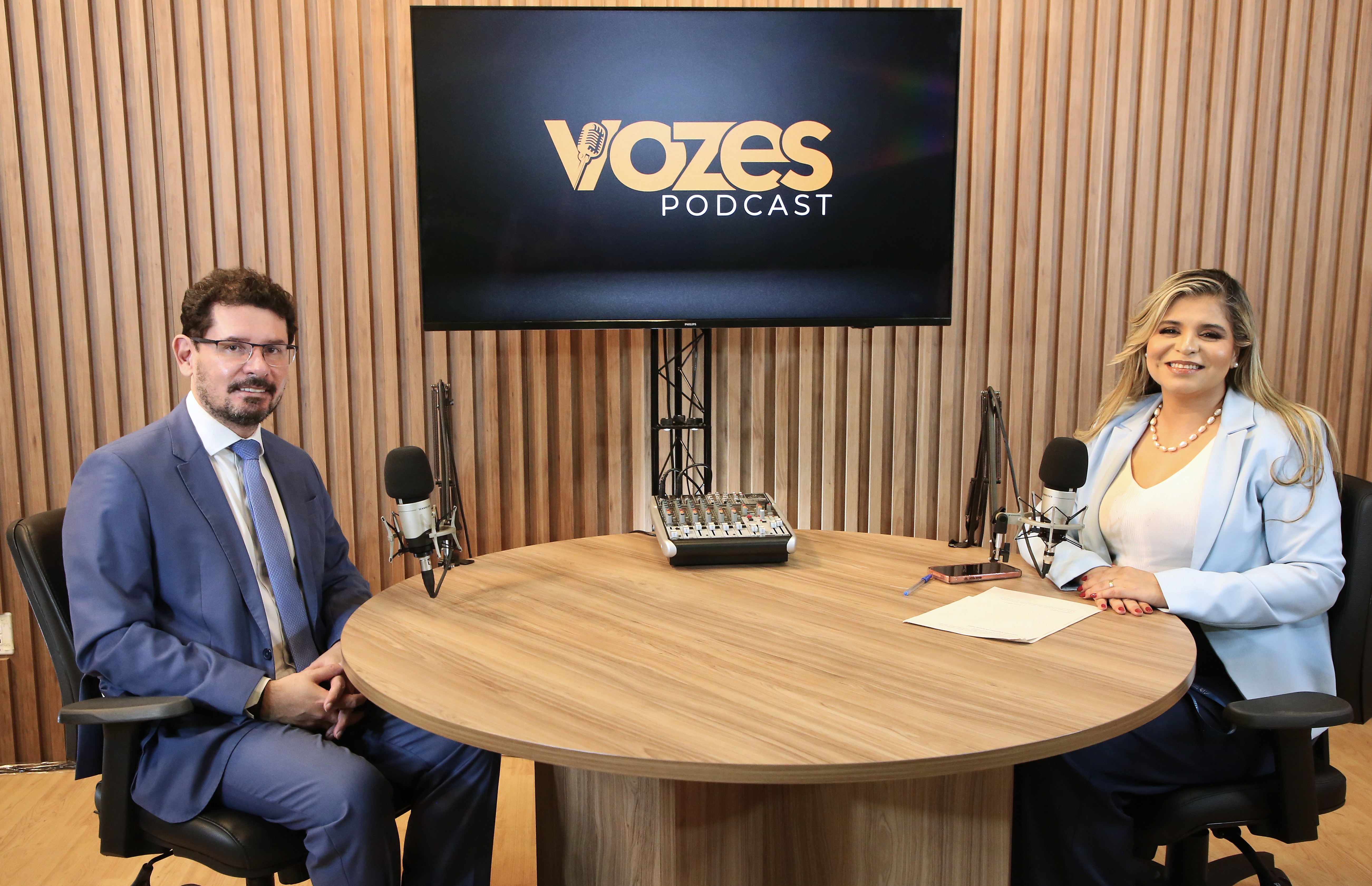 A imagem mostra o juiz coordenador da Coordenadoria da Cidadania (Cocid), Márcio Soares da Cunha, e uma apresentadora sentados diante de microfones, durante a gravação do Podcast Vozes.