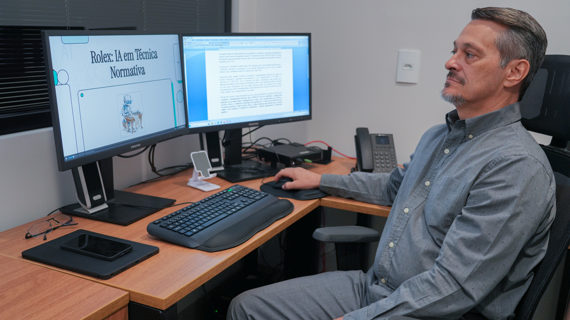 A imagem mostra o servidor do TJTO sentado e atrás dele dois monitores de ligados no site do Tribunal.. 