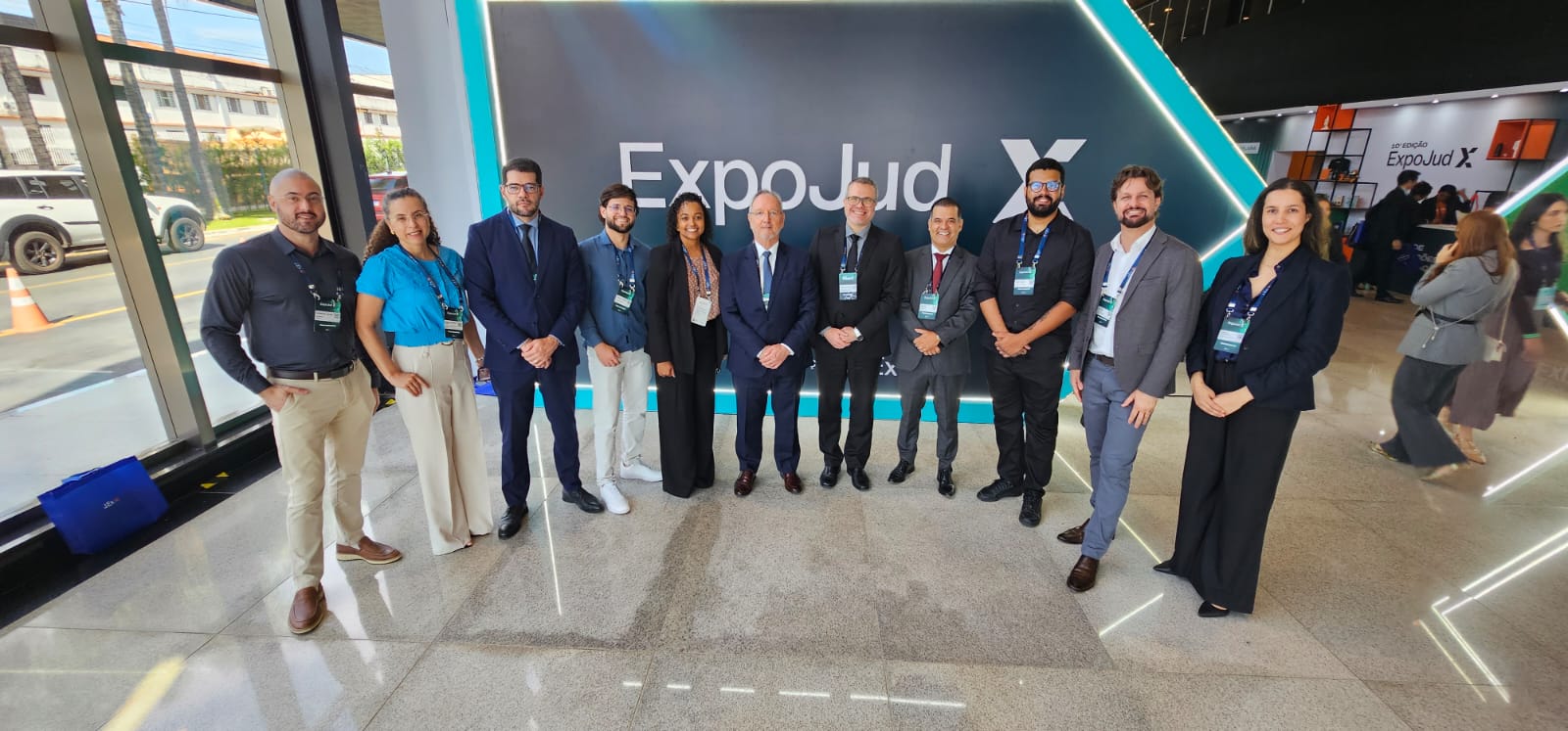 Corregedor, magistrados e servidores posam para foto durante o 10º Expojud, em Brasília. O grupo de onze pessoas está em pé, lado a lado, diante de um painel com o nome do evento.