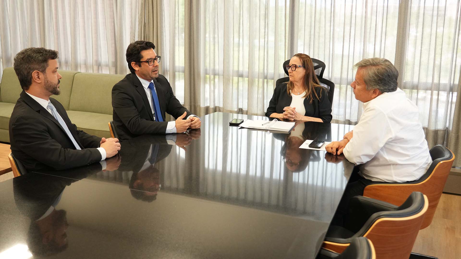 A presidente do TJTO, desembargadora Maysa Vendramini Rosal, durante reunião com representantes do Judiciário e do Ministério Público para alinhar as ações do Mês Nacional do Júri 2026. Na imagem, quatro participantes estão sentados ao redor de uma mesa de reuniões.
