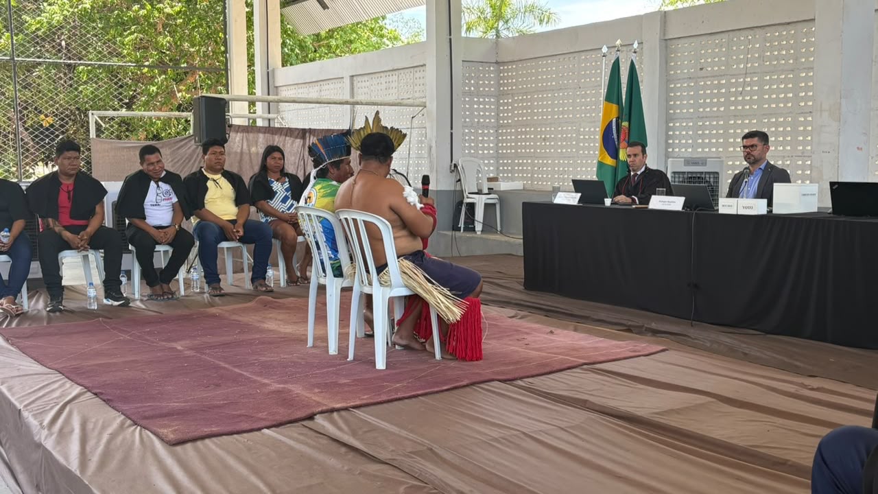 Pessoas em simulação de um tribunal do júri dentro de ginásio em uma aldeia indígena