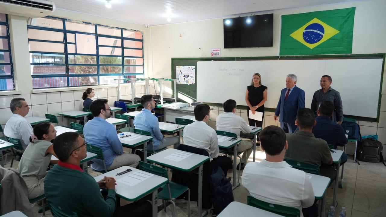 Imagem mostra candidatos do concurso sentados em uma sala e membros da comissão do concurso a frente do quadro branco