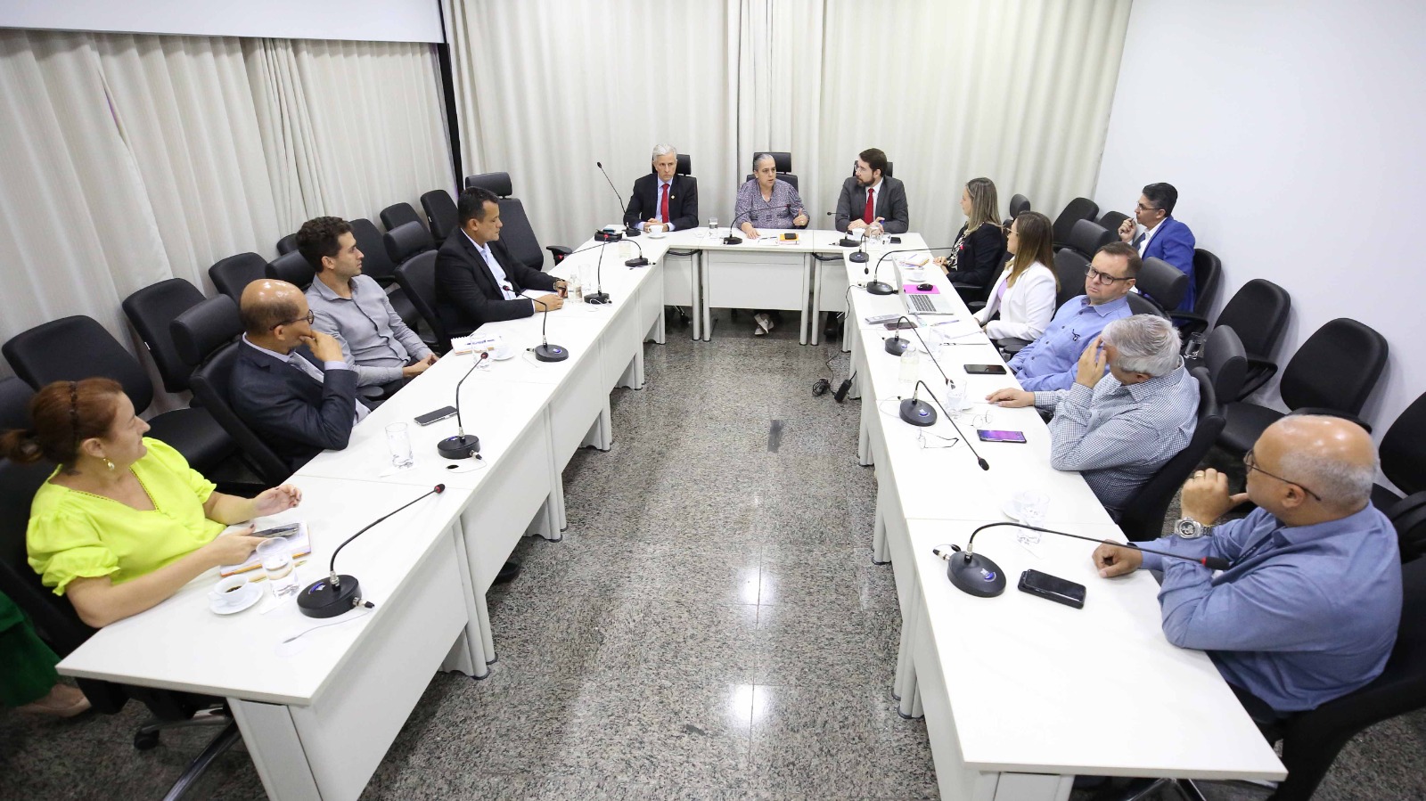 Sala com uma mesa em U com diretores, juízes e a desembargadora Jacqueline Adorno sentados em reunião