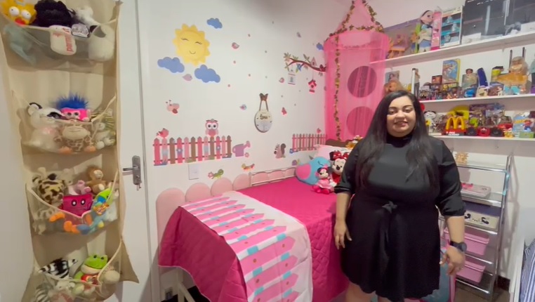 Evi, de roupa preta, no quarto com o tema jardim encantado