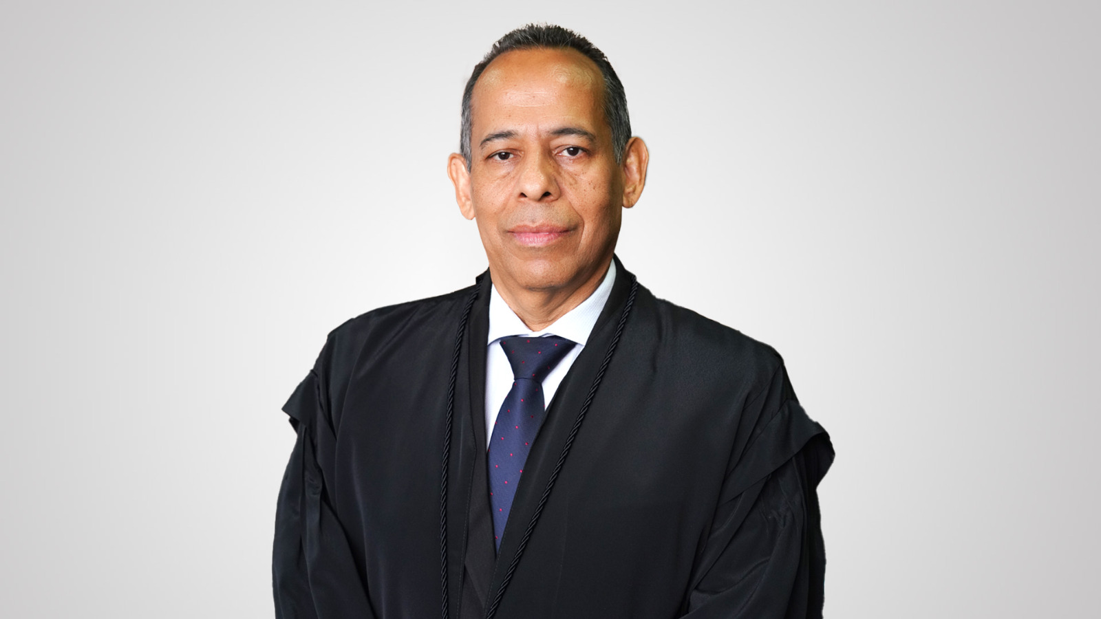 Desembargador Jão Rodrigues Filho é um homem moreno, usa toga preta, camisa branca e gravata azul com detalhes em vermelho