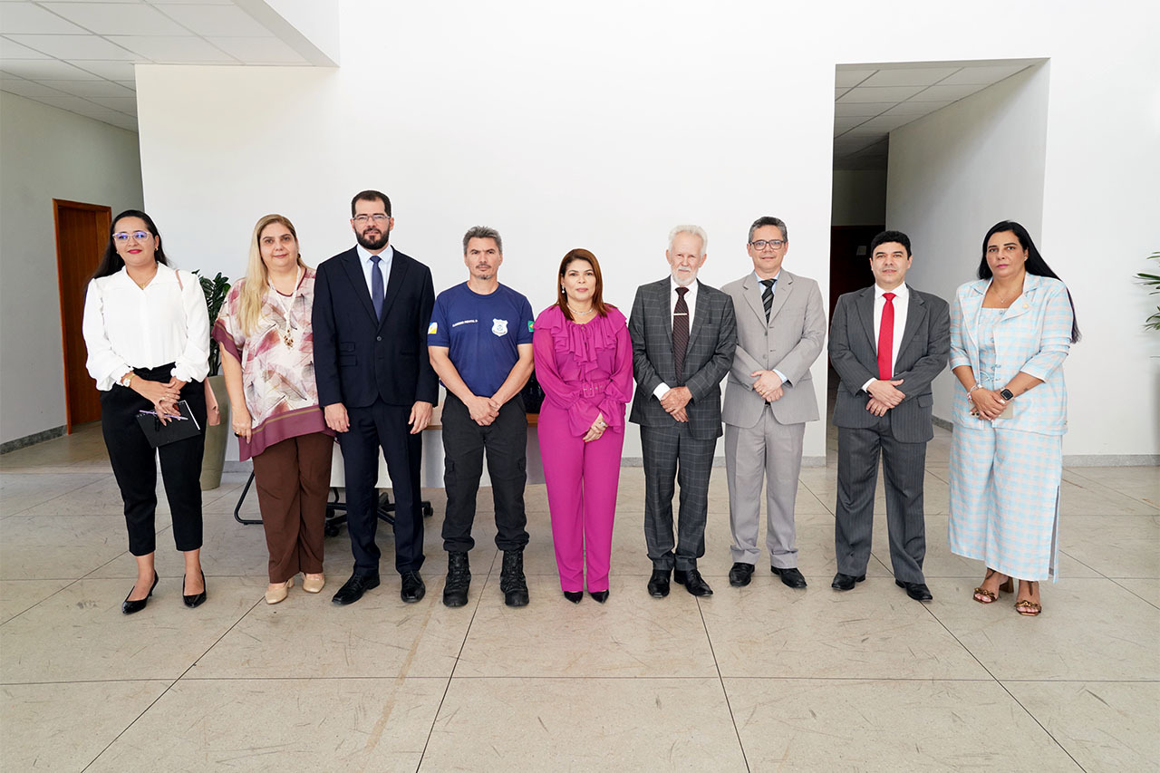 Em umas das salas com paredes brancas do local, o presidente João Rigo posa para foto ao lado de autoridades que integram a equipe do NAI