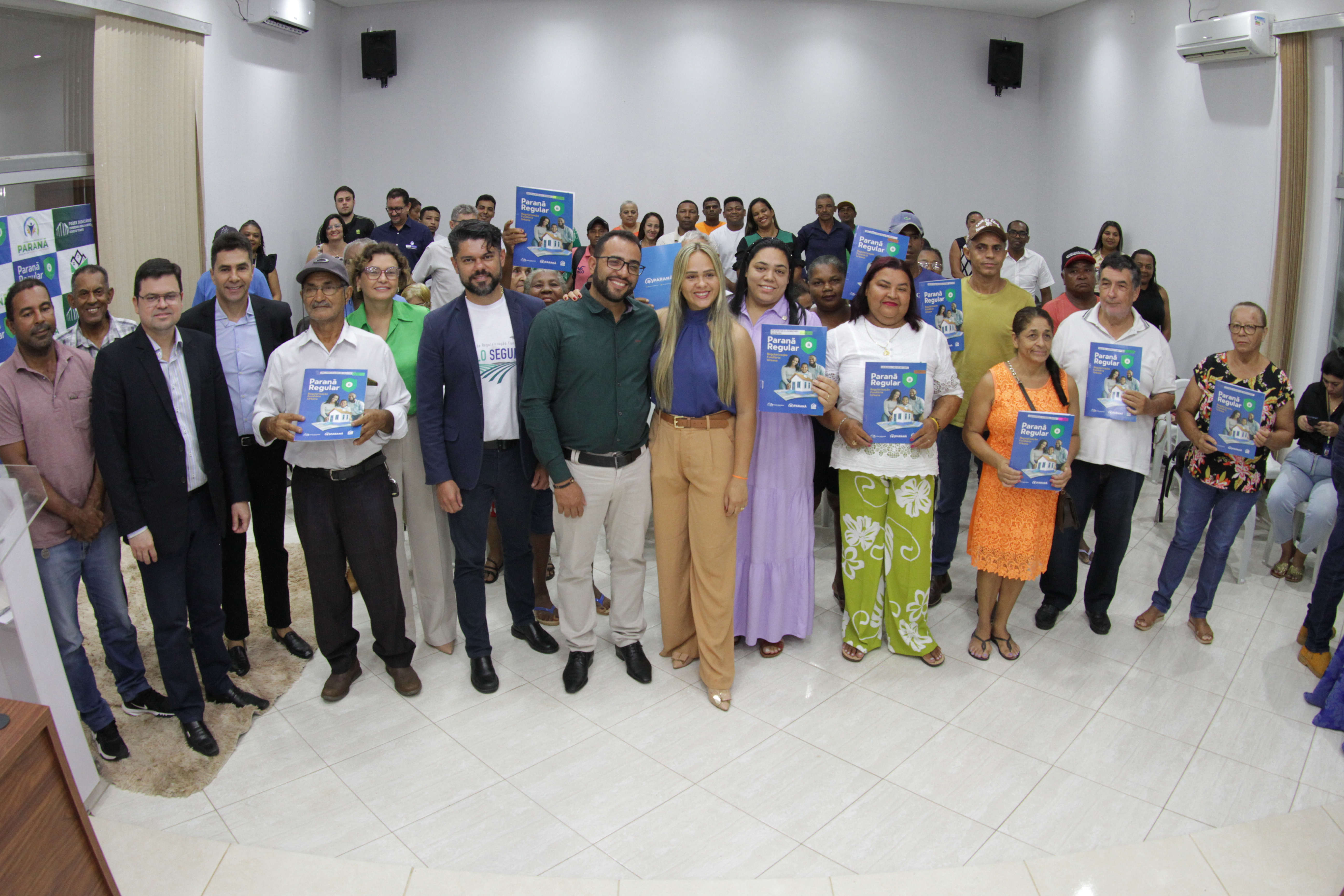 Pessoas posam para foto, algumas seguram um documento na frente do corpo