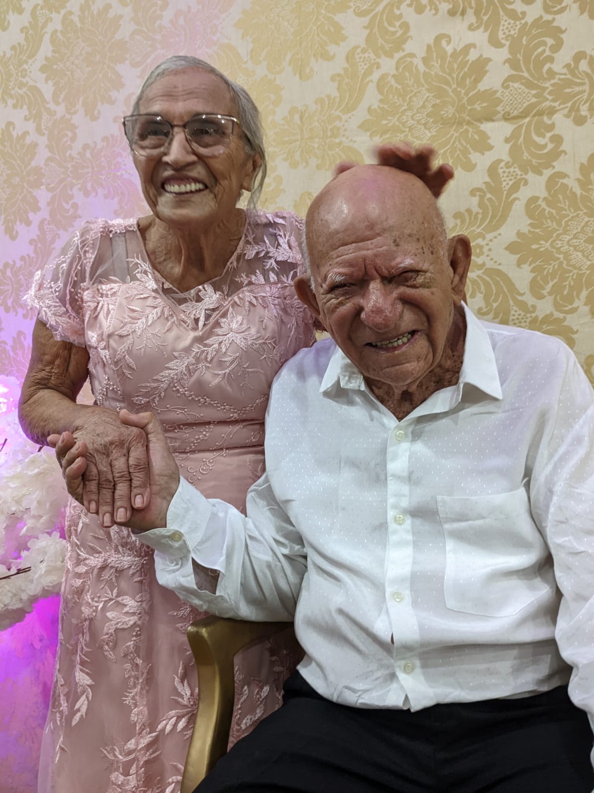 casal de idosos, Marcionilio José Nunes, 82 anos, e Maria Severina Mandu, 79, se casaram depois de 42 anos, Ela está de vestido rosa e usando óculos; e ele de camisa branca e calça preta. 