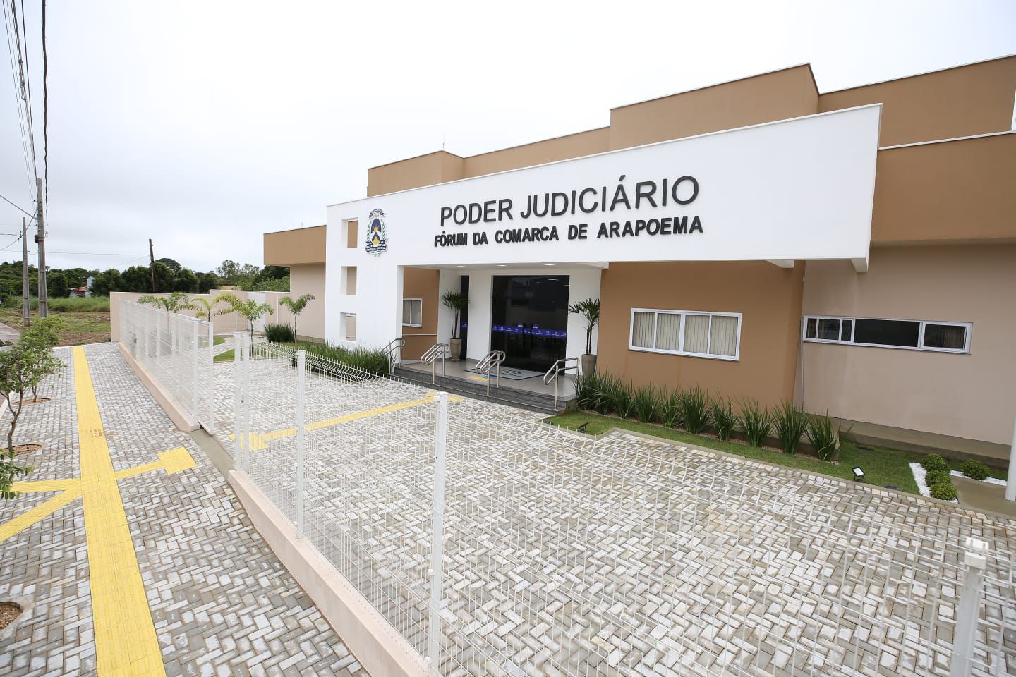 A imagem mostra a fachada do prédio da Comarca de Arapoema, pintada em tons de bege e branco.