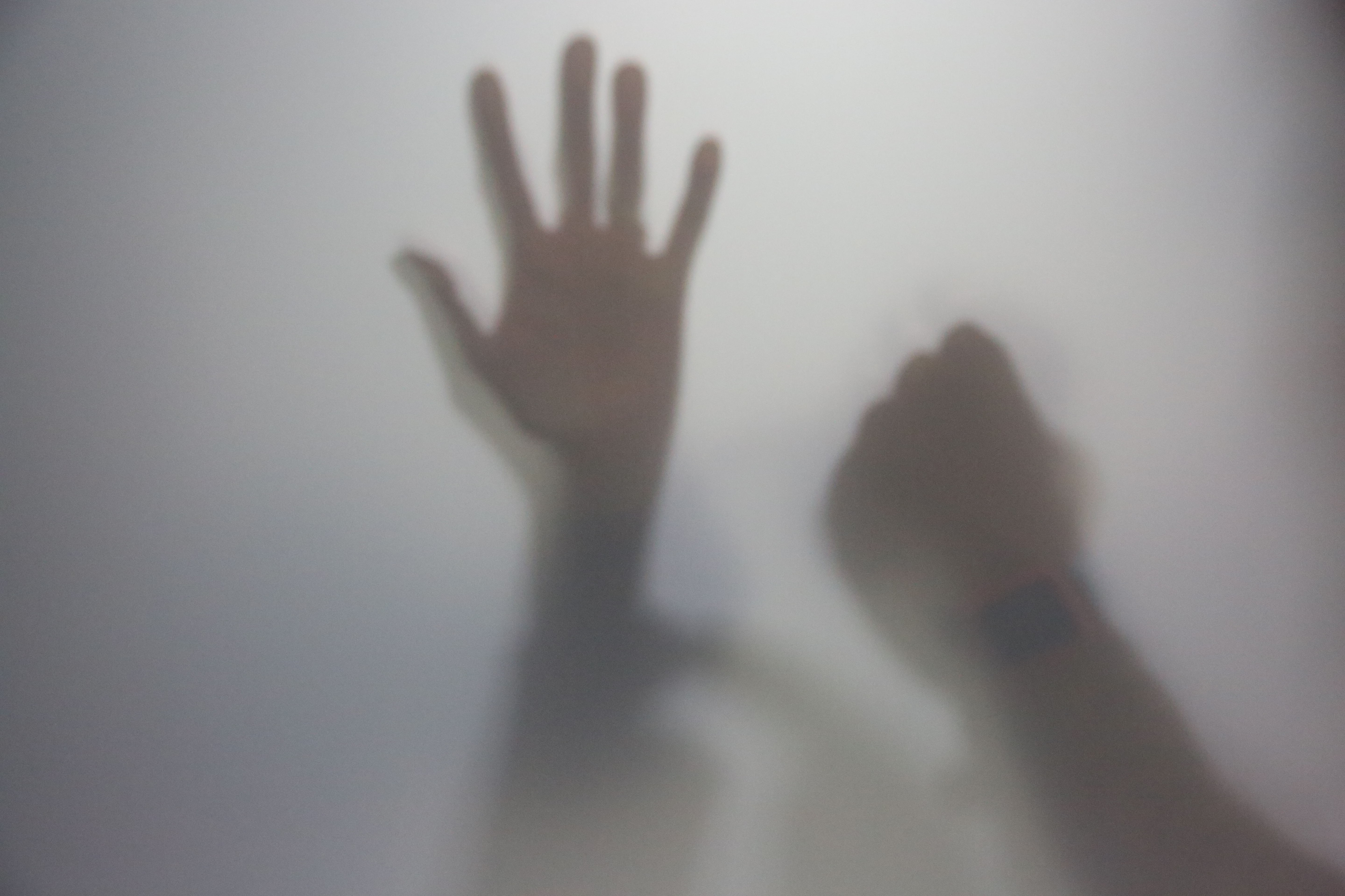 Imagem ilustrativa da sombra de uma mão aberta de uma mulher e a de um homem, fechada, representando a violência doméstica 