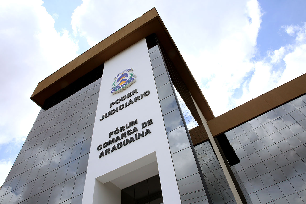 Detalhe da fachada da Comarca de Araguaína, com paredes com vidraças e um detalhe em branco com a logo e nome Poder Judiciário, Fórum da Comarca de Araguaína