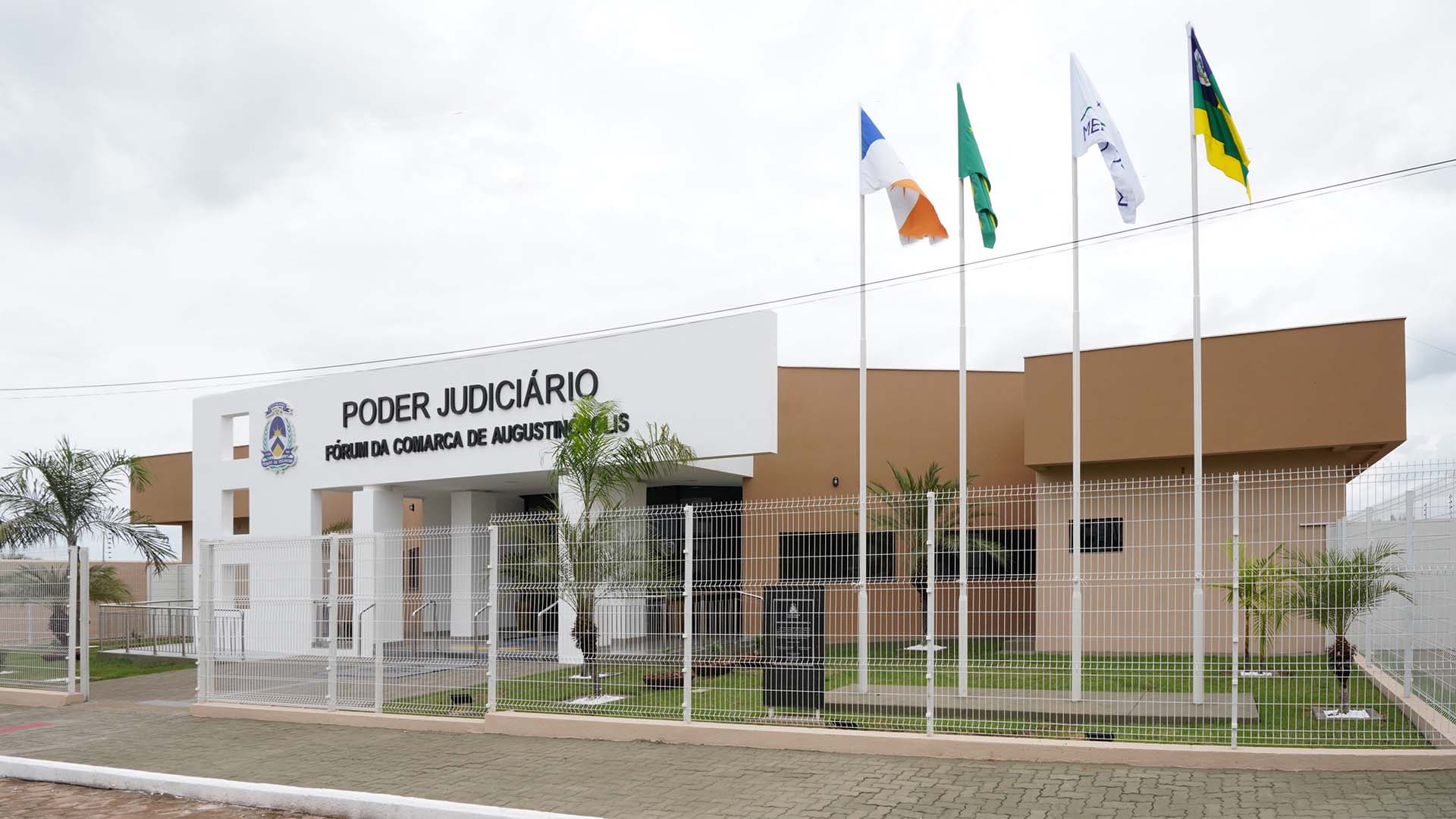 Fachada frontal na cor branca e o nome da comarca de Augustinópolis, com a visão das colunas de sustentação e escadas de acesso