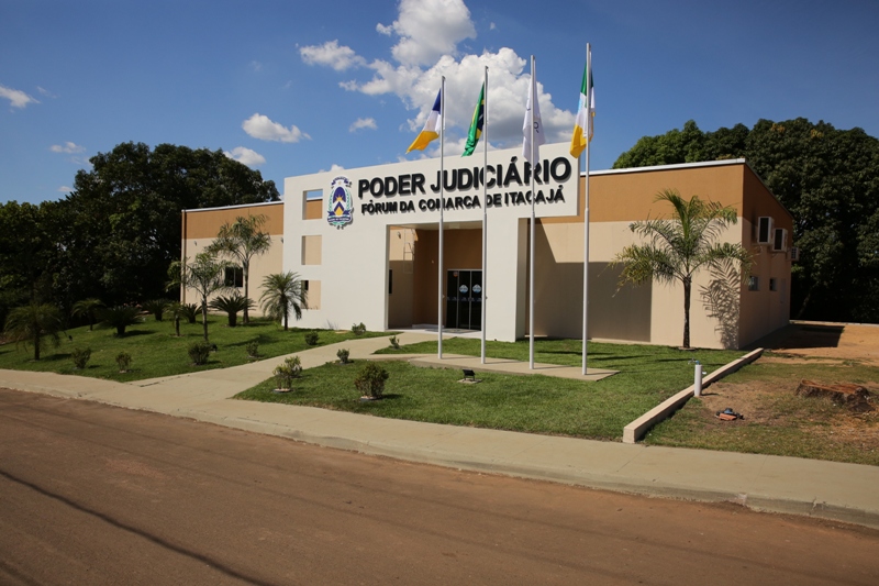 Fórum de Itacajá com destaque para o letreiro "Poder Judiciário". O prédio tem bandeiras e árvores com um céu claro e algumas nuvens.
