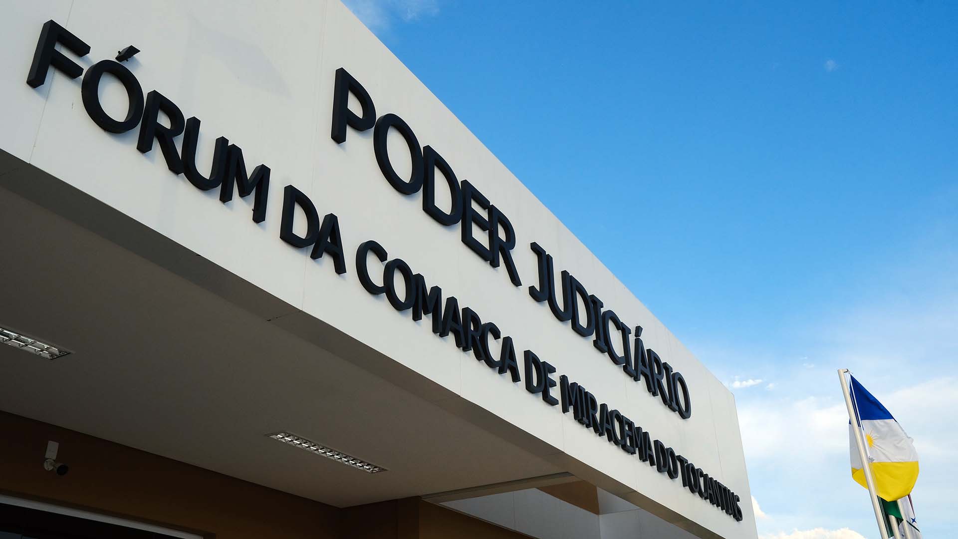 Detalhe da fachada do prédio do Fórum de Miracema com placa na cor branca e letreiro na cor preta com o nome escrito em letras pretas