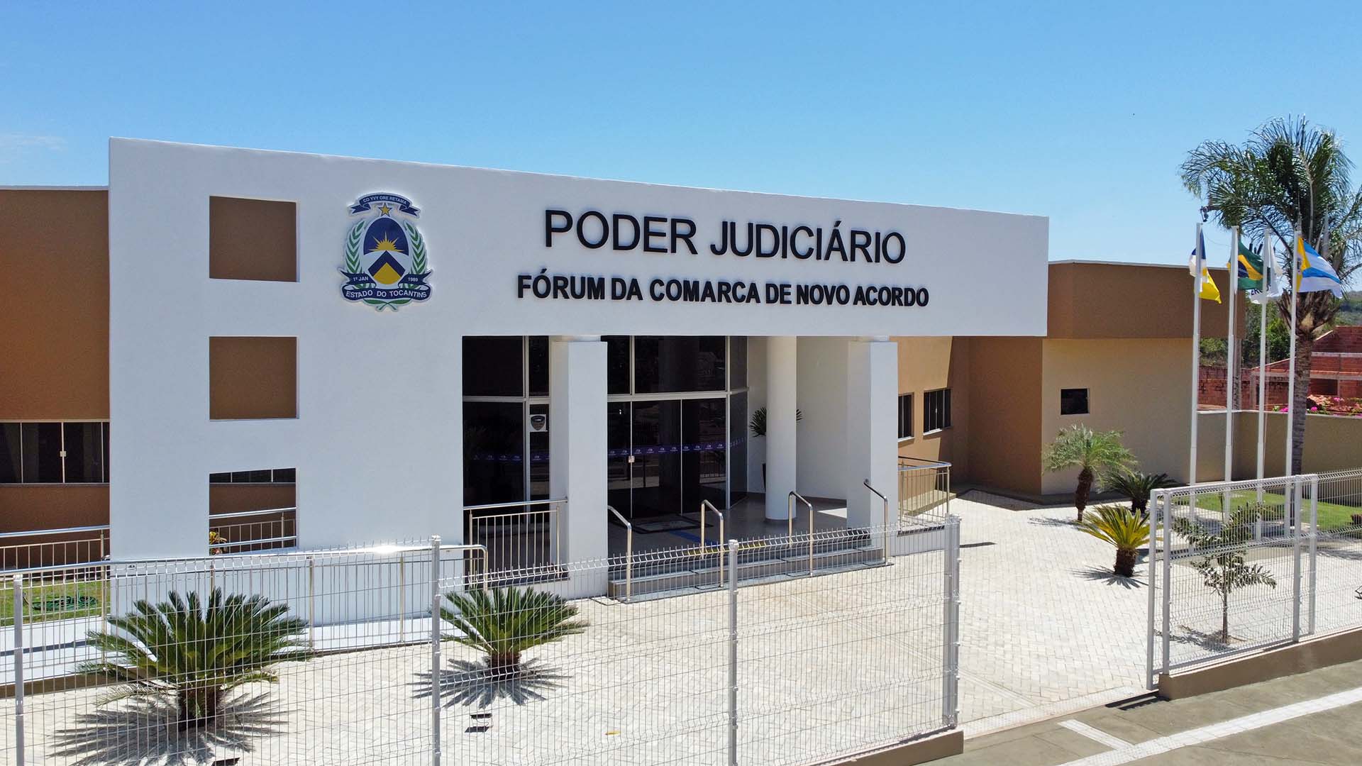 Fachada principal do fórum de Novo Acordo, na cor branca. O prédio tem a cor marrom e possui cerca de segurança