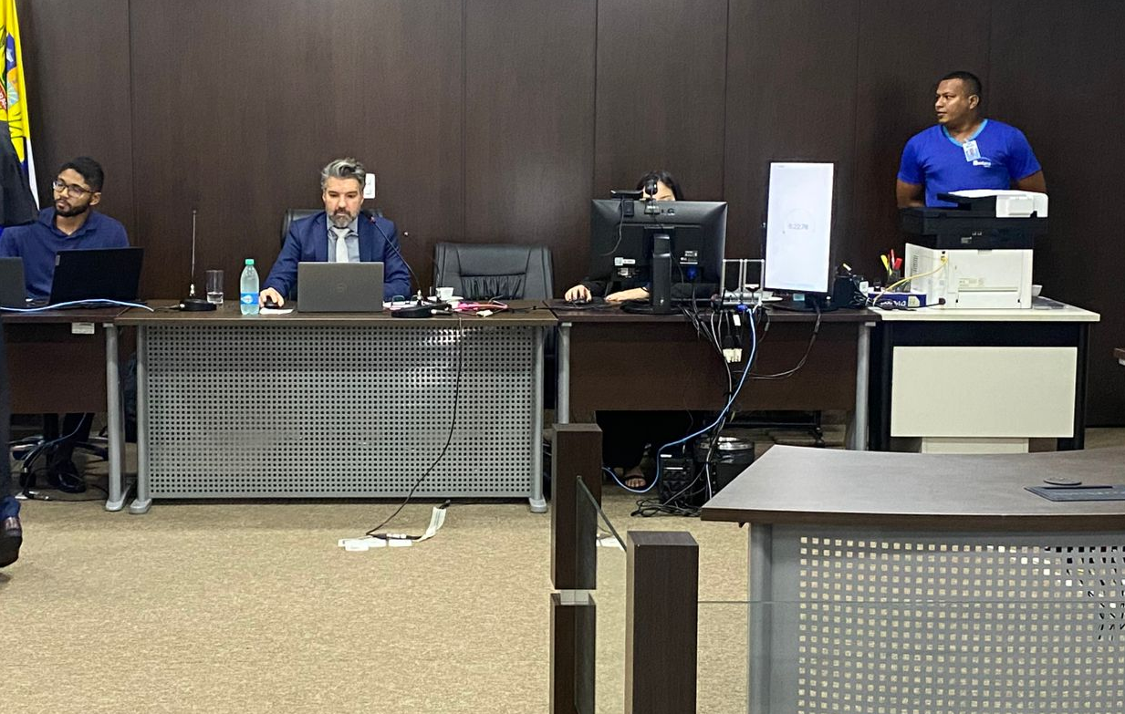 Juiz Marcelo Rostirolla sentando em sua mesa, e servidores da Justiça ao lado, durante julgamento do tribunal do júri de Araguacema