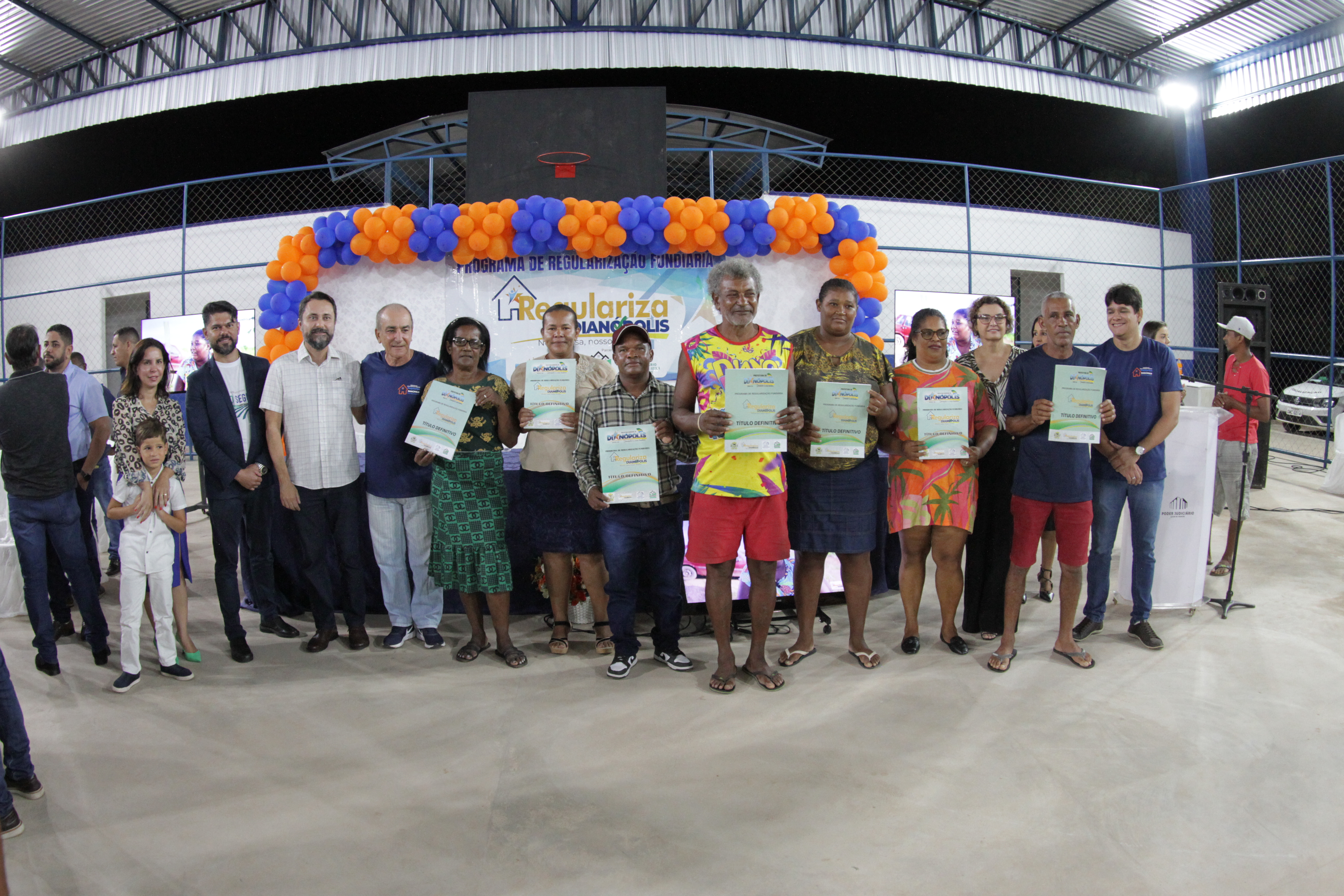Pessoas posam para foto, algumas seguram um documento em frente ao corpo