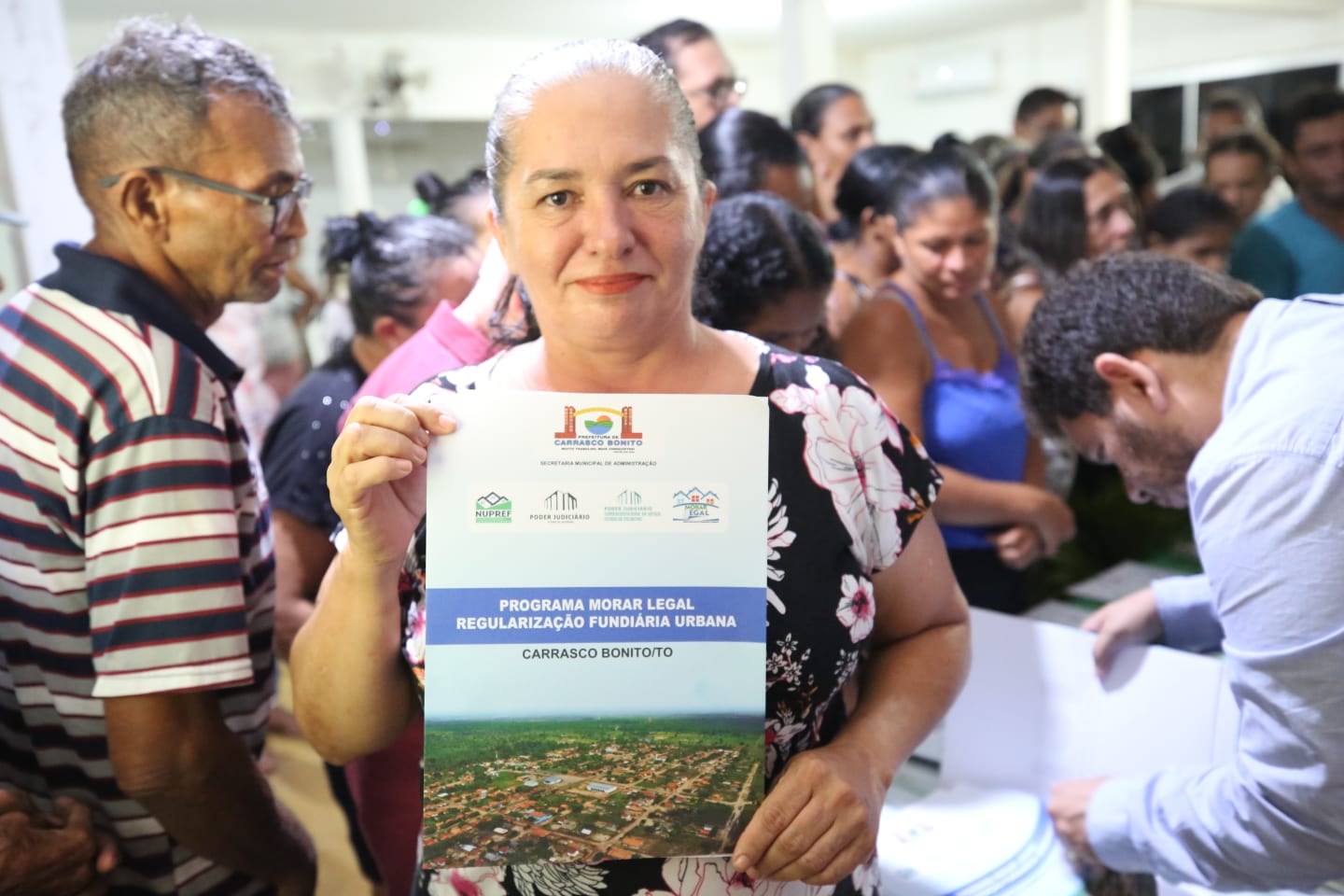 Maria Enídia Cardoso da Silva segurando seu título de legitimação fundiária