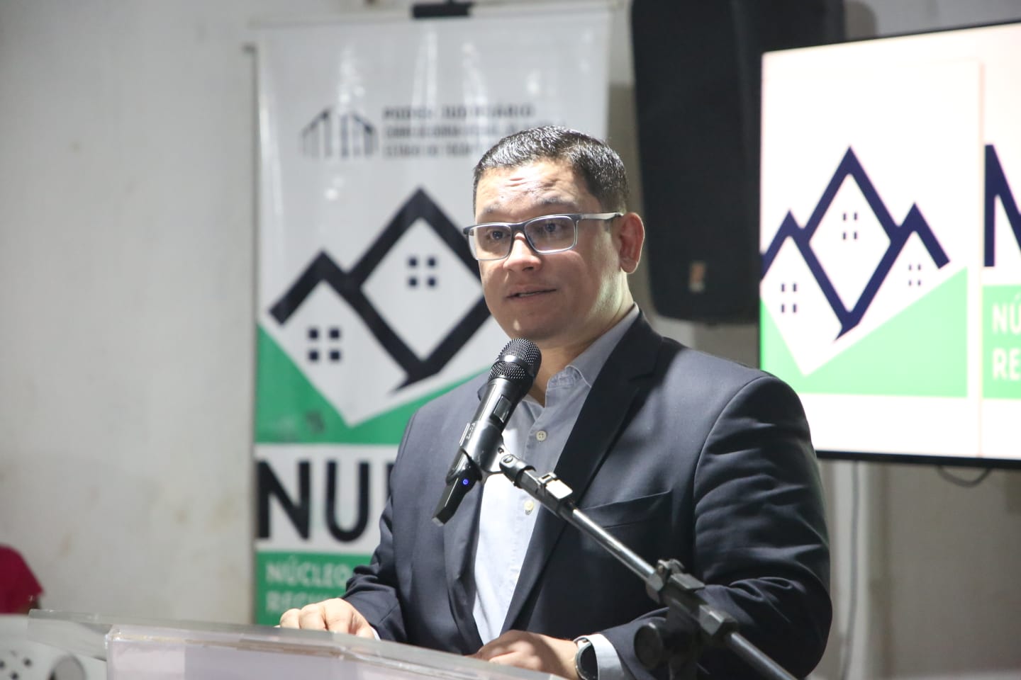 juiz Jefferson Azevedo, diretor do Foro da Comarca de Augustinópolis de terno cinza discursa durante entrega de títulos de legitimação fundiária