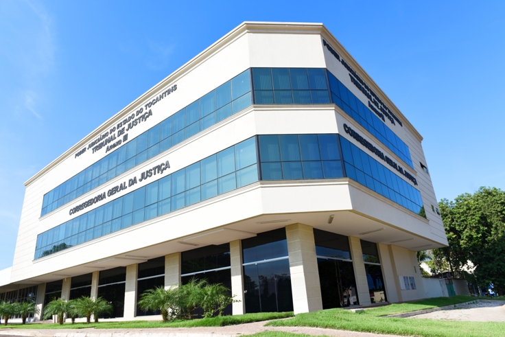 Fotografia colorida da fachada da Corregedoria Geral de Justiça do Estado do Tocantins com alguns coqueiros na frente