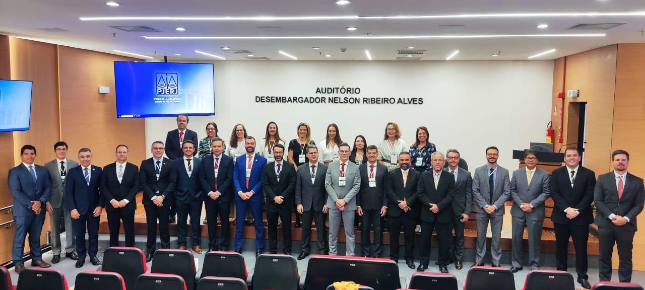 Grupo de magistrados e servidores posando para foto em um auditório.
