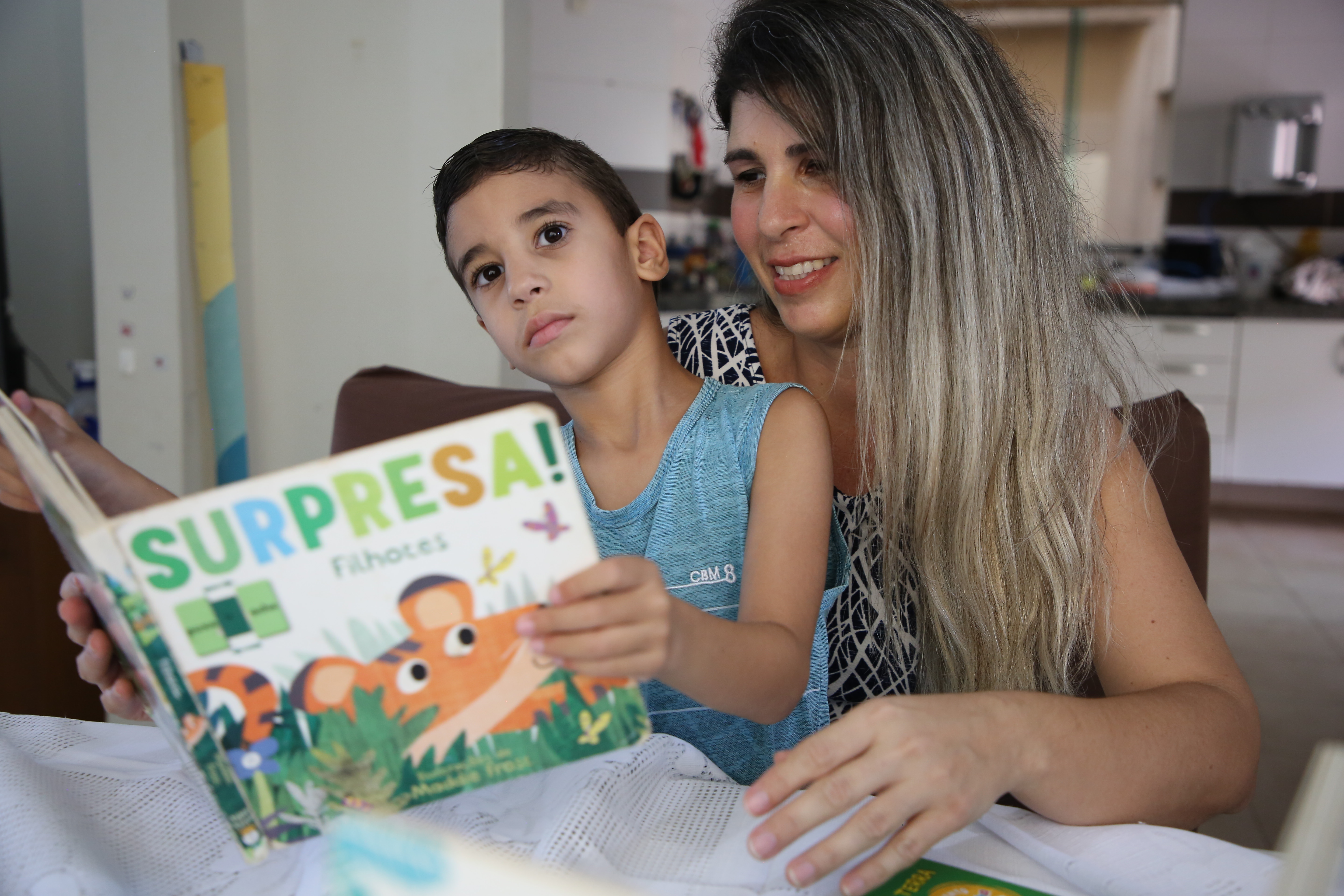 Luciana, com João Pedro no colo, com um livro nas mãos 