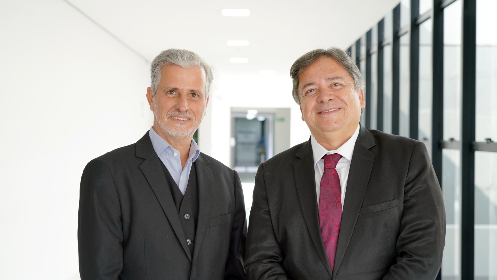 O juiz Esmar Custódio Vêncio Filho  ao lado do juiz Arióstenis Guimarães Vieira no corredor do Tribunal de Justiça. Ambos usam paletó escuros