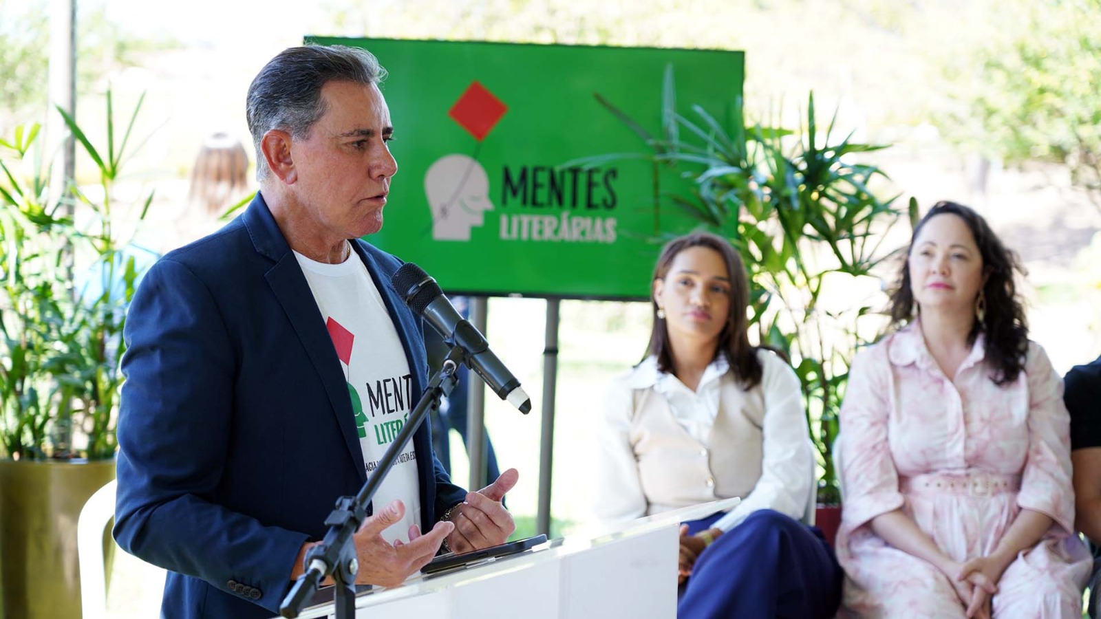 conselheiro do CNJ, José Rotondano, está falando ao microfone. Ele usa camiseta branca com a logo do projeto e um blazer azul marinho 