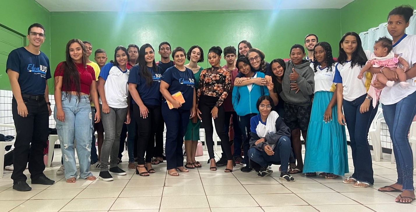 Pessoas posam para foto em sala de aula com parede verde e chão com azulejo branco