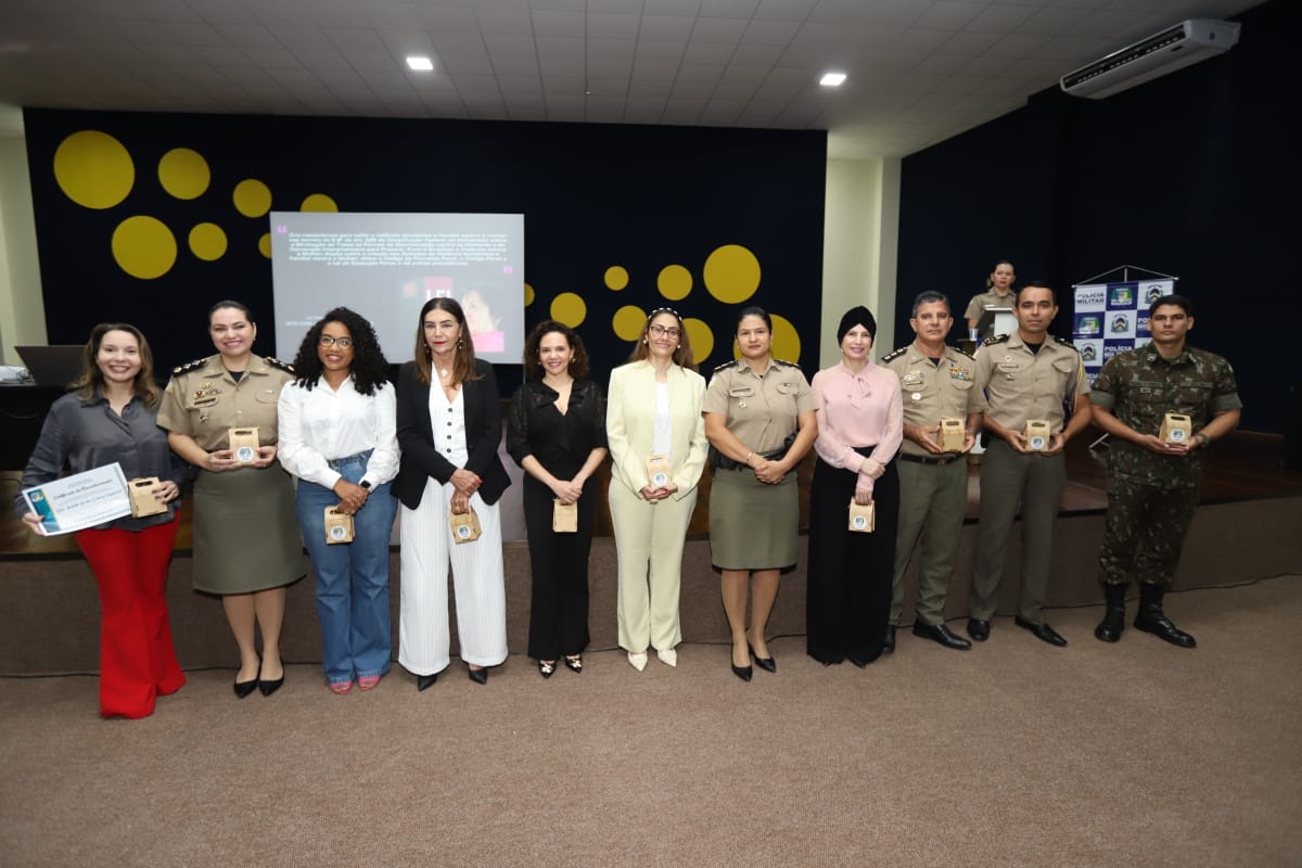 Pessoas posam para foto, algumas seguram seguram uma embalagem marrom clara nas mão